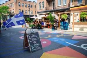 Lively Montreal street with Quebec flag and outdoor cafe setting.