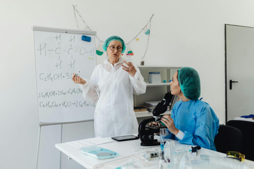 pexels-photo-8539646-8539646 Female scientists in protective gear discussing chemical formulas in a laboratory.