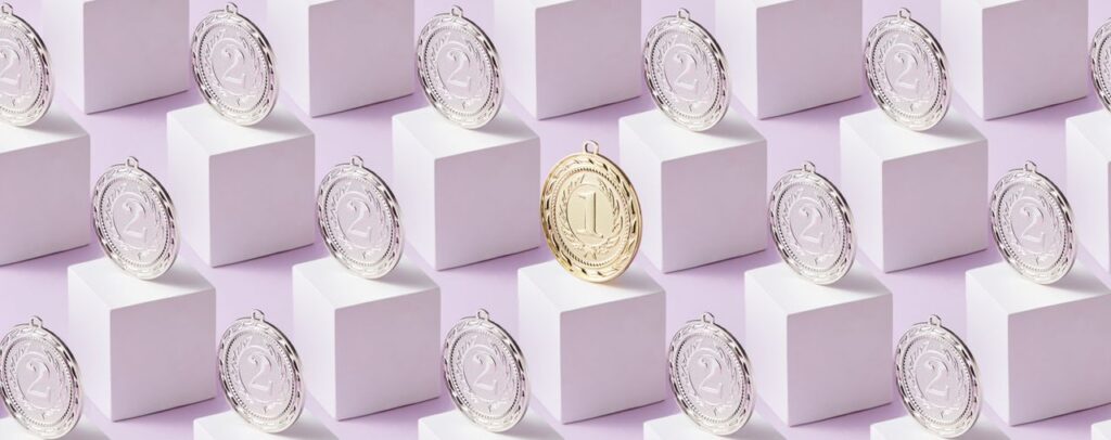A gold medal stands out among silver medals on white cubes, showcasing uniqueness.
